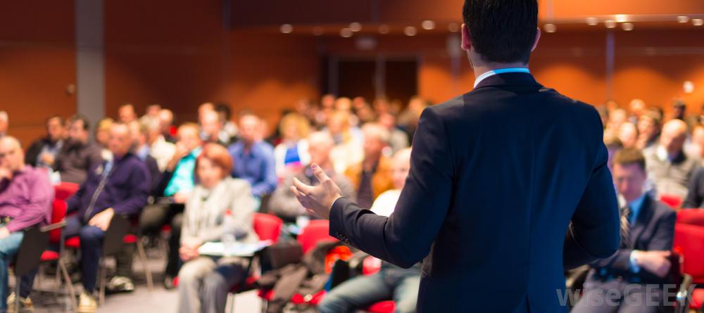 man-in-suit-speaking-to-audience-in-front-of-him